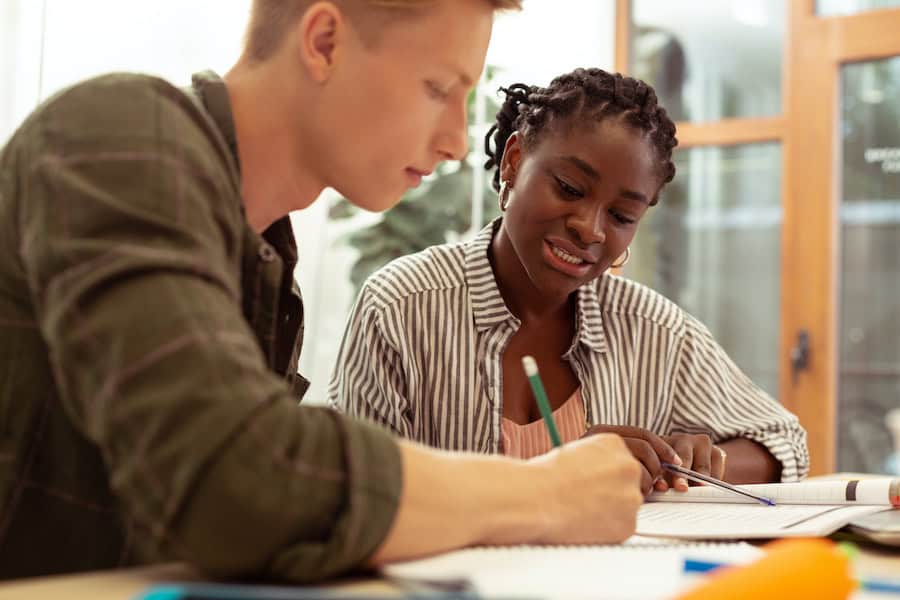 Concentrated young male person completing task with tutor